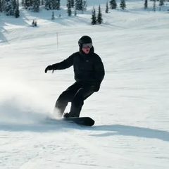 Eine Person auf dem Snowboard am Schneehang